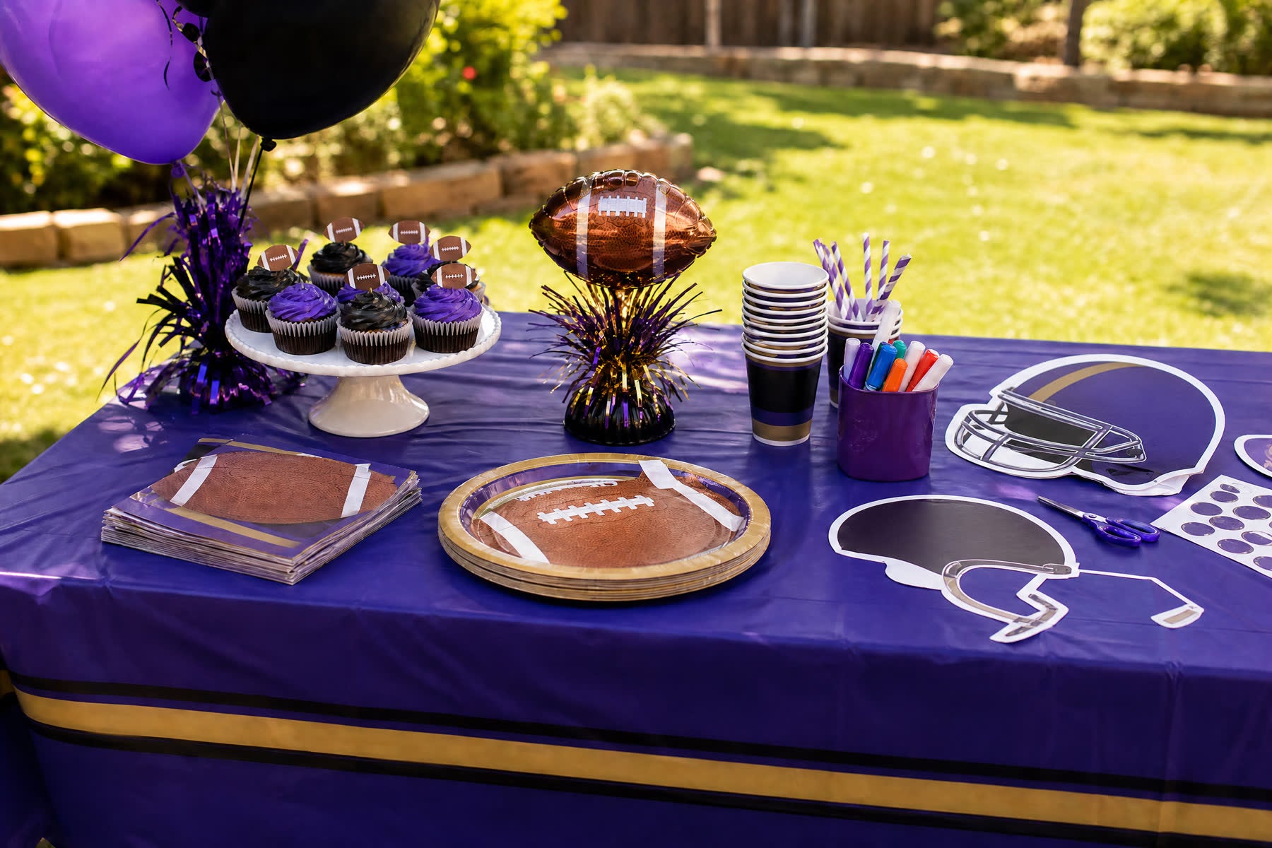 Purple and black football birthday party table with paper tableware and football decorations